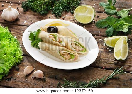 Restaurant food. Catering, buffet. Served dishes. Restaurant meals. Restaurant food - crepes rolls filled with salty salmon. Pancake, crepes rolls at wood. Served wooden table.