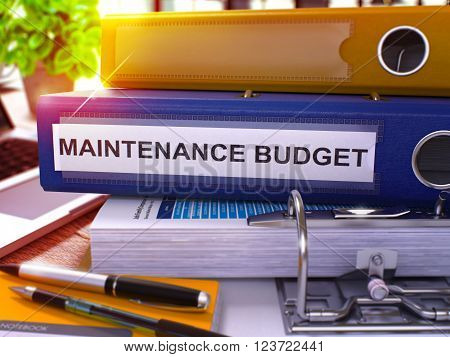 Blue Office Folder with Inscription Maintenance Budget on Office Desktop with Office Supplies and Modern Laptop. Maintenance Budget Business Concept on Blurred Background. 3D Render.