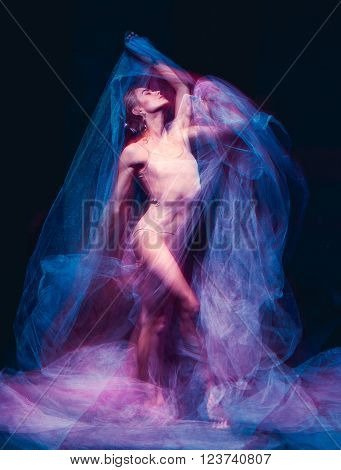 The photo as art - a sensual and emotional dance of beautiful ballerina through the veil on a dark background. A stroboscopic image of the one model