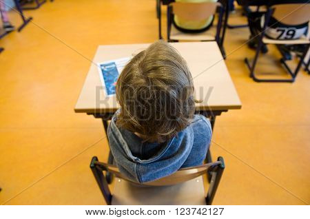 ENSCHEDE, NETHERLANDS - MAR 22, 2016: Child of 11 years old sitting behind his desk in a school class.