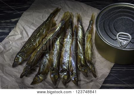 Smoked capelin and conserve tins on dark wooden background