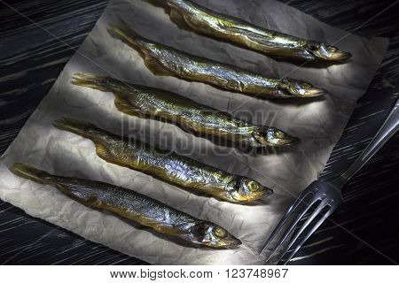 Smoked salted capelin on vintage wooden background, top view
