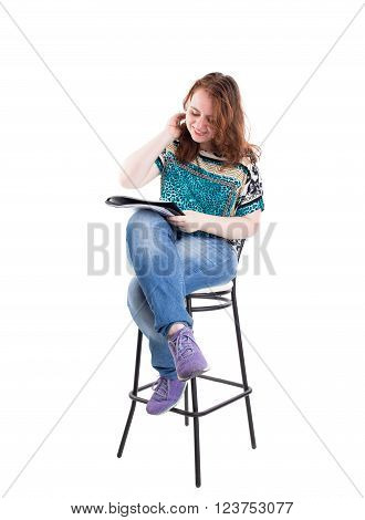 Beautiful smiling redhead plus size wreckled model with folder and ballpoint pen sitting on the bar chair. Isolated on a white background.