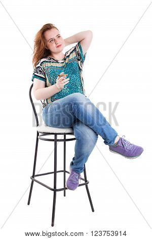 Smiling redhead plus size wreckled model sitting on the bar chair with cigar. Studio shot. Isolated on a white background.