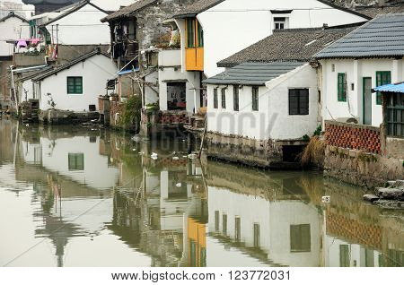 Old buildings in traditional Asian architecture lining a dirty water canal in Sijing Ancient town located in Songjiang district of Shanghai China.