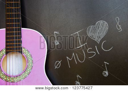 Music school for children with purple guitar closeup on blackboard background