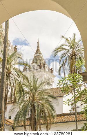 Low angle courtyard view of one of the towers of the ancient San Franciso catholic church located in the historic center of Quito in Ecuador.
