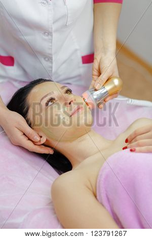 Face Skin Care. Young beautiful woman with dark hair gets procedure in the beauty salon.  Ultrasound Cavitation anti-aging, Rejuvenation, Lifting Procedure. Beauty Concept