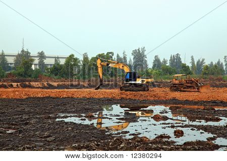 afspejling af gravemaskine Loader med rendegraver stående i sandkasse