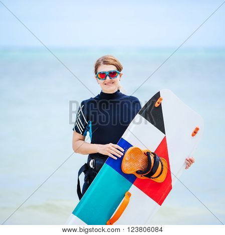 Wakeborder girl at the tropical beach with her surfboard