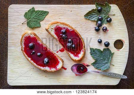 Bread with jelly currant on kitchen wooden table