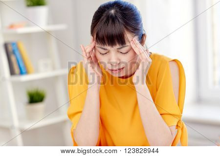 people, healthcare, stress and problem concept - unhappy asian young woman suffering from headache at home