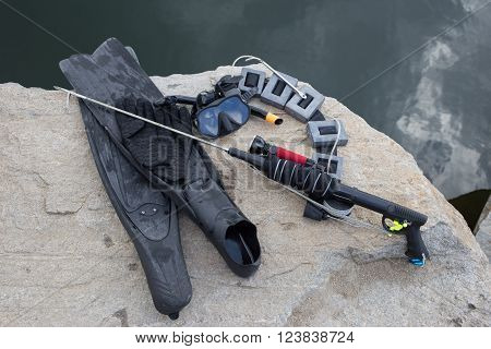 Equipment for underwater hunting near the pond on the rock.