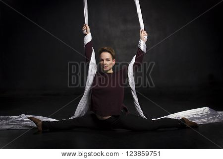 Aerialist woman doing some flexibility and strength tricks on silks