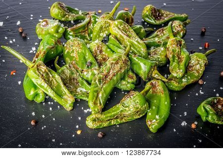 Grilled padron peppers with salt and pepper on black slate plate