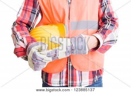 Builder or construction worker pulling out glove after work while holding helmet underarm