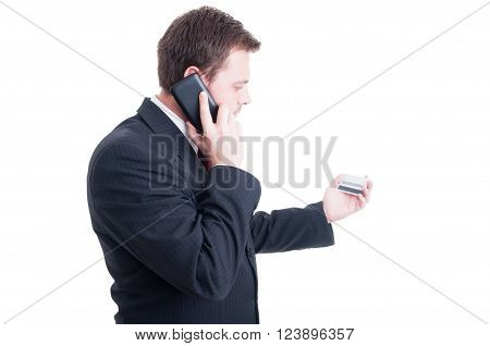 Financial mobility concept or e-banking with elegant businessman reading code number from credit card while talking on the phone
