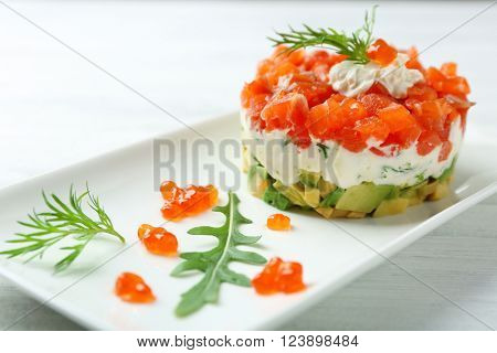 Delicious salmon tartare with red caviar on white plate