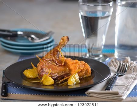 Duck a La Orange served on dark ceramic plate on blue striped place mat