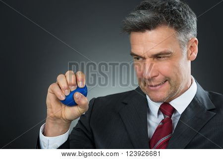 Businessman Pressing Stressball In Hand Over Black Background