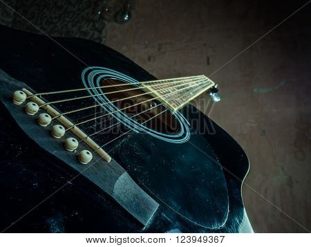 Closeup photo of an acoustic guitar on dark grungy background. Background image for musical projects.