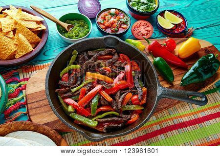 Beef fajitas in a pan with sauces chili and sides Mexican food