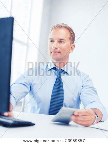 business, office, tax, school and education concept - smiling businessman with calculator, computer and papers