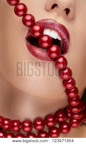Red pearls in a mouth with red lipstick