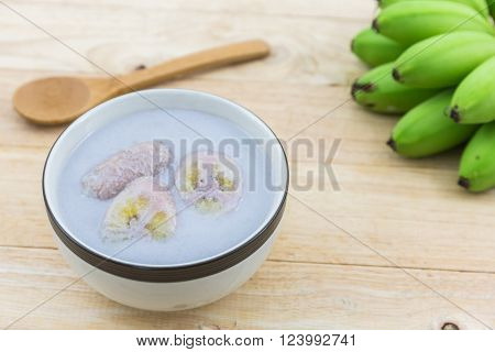 Banana in coconut milk (Kluay Buad Chee) on wood desk Thai desert.