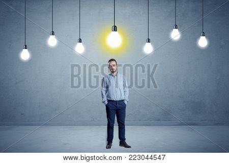 Handsome businessman in an empty space with bulbs above and uninspired face