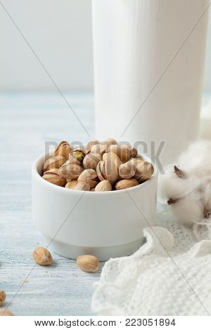Pistachios in a ceramic white cup on a white wooden background