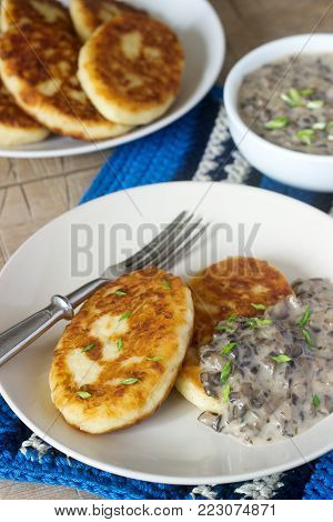 Potato cutlets or pancakes with mushroom sauce and green onions. Rustic style, selective focus.