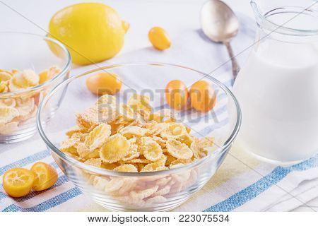 Bowl with corn flakes, jug of milk and empty bowl for prepared delicious breakfast.The concept of healthy breakfast, corn flakes with milk and fruit on wooden table, close up.
