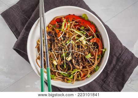 Healthy vegan buckwheat noodles with a mix of vegetables, sprouts and nut-soy sauce. Vegetarian padthai soba noodles in white bowl