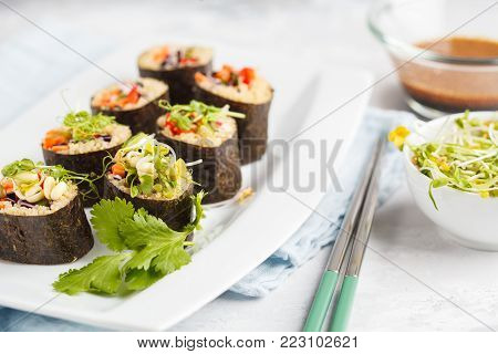 Vegan sushi rolls with quinoa, vegetables and soy-nut sauce on a white plate. Vegan Healthy Food Concept.