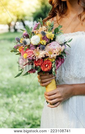 Beautiful Bride Holding Wedding Flower Bouquet In Hands Outdoors