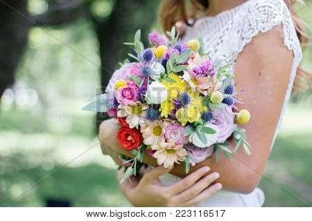 Beautiful Bride Holding Wedding Flower Bouquet In Hands Outdoors