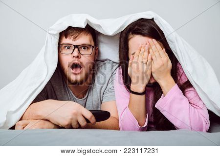 man with woman watchin scared movie under the blanket