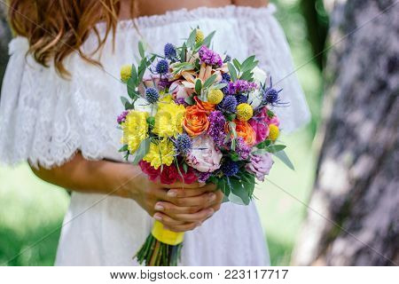 Beautiful Bride Holding Wedding Flower Bouquet In Hands Outdoors