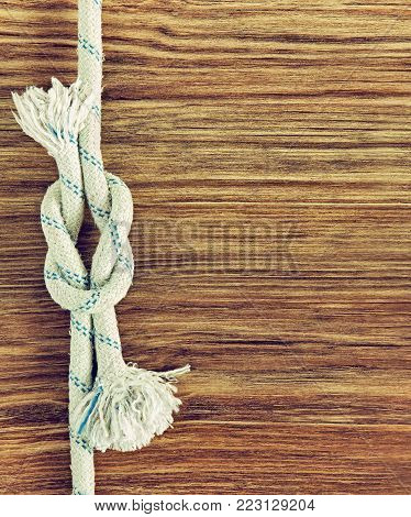 White rope and nautical reef knot on grunge wooden background.Empty space for text.