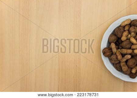 plate of nuts on wooden table top view with empty space