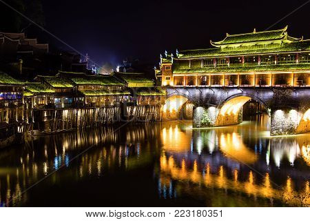 Hong Bridge at night in Fenghuang Ancient town, Hunan province, China. This ancient town was added to the UNESCO World Heritage Tentative List in the Cultural category.