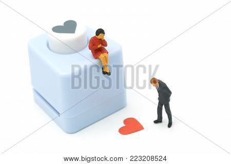 couple Miniature 2 people standing with Heart shaped punching machine Punch red paper Red heart is the promise of love.  as background Valentine concept with copy spaces for your text or design.