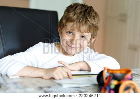 Tired little kid boy at home making homework at the morning before the school starts. Little child doing excercise, indoors. Elementary school and education