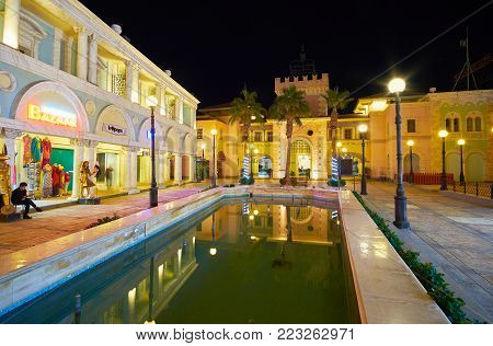 SHARM EL SHEIKH, EGYPT- DECEMBER 15, 2017: The fountain in Il Mercato shopping street reflects the lighted buildings and replica of castle tower in Italian style, on December 15 in Sharm El Sheikh.