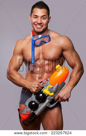 muscular man with water gun and with swimming equipments