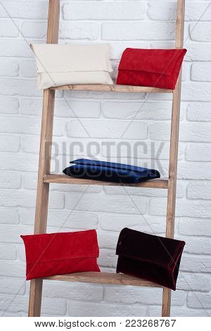 Close-up of five trendy red, white, blue and burgundy women s bags, laying on the white wall background. Good choice for casual look and foe evening dress with high heels.