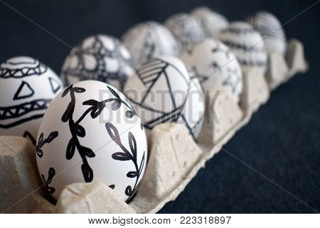 Many Easter Eggs With Doodle Graphic Patterns In Carton Packing On A Dark Background. Pascha Eggs Wi