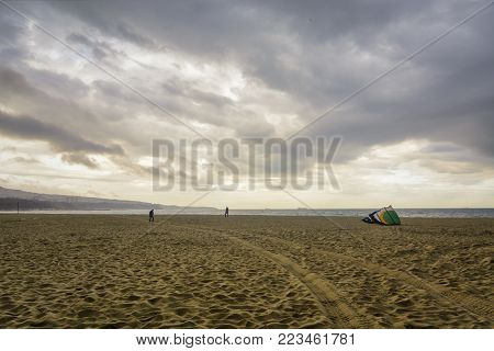 beach after the storm , some people preparing for kitesurf