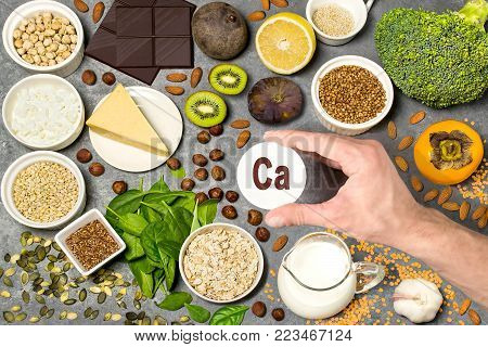 Food rich in calcium. Various natural sources of vitamins and micronutrients. Useful food for health and balanced diet. Prevention of avitaminosis. Man's hand holds tag with name of calcium